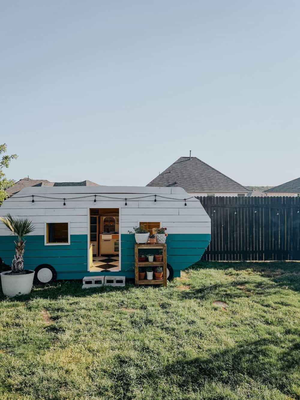 Backyard with a camper playhouse and plants on a plant stand 