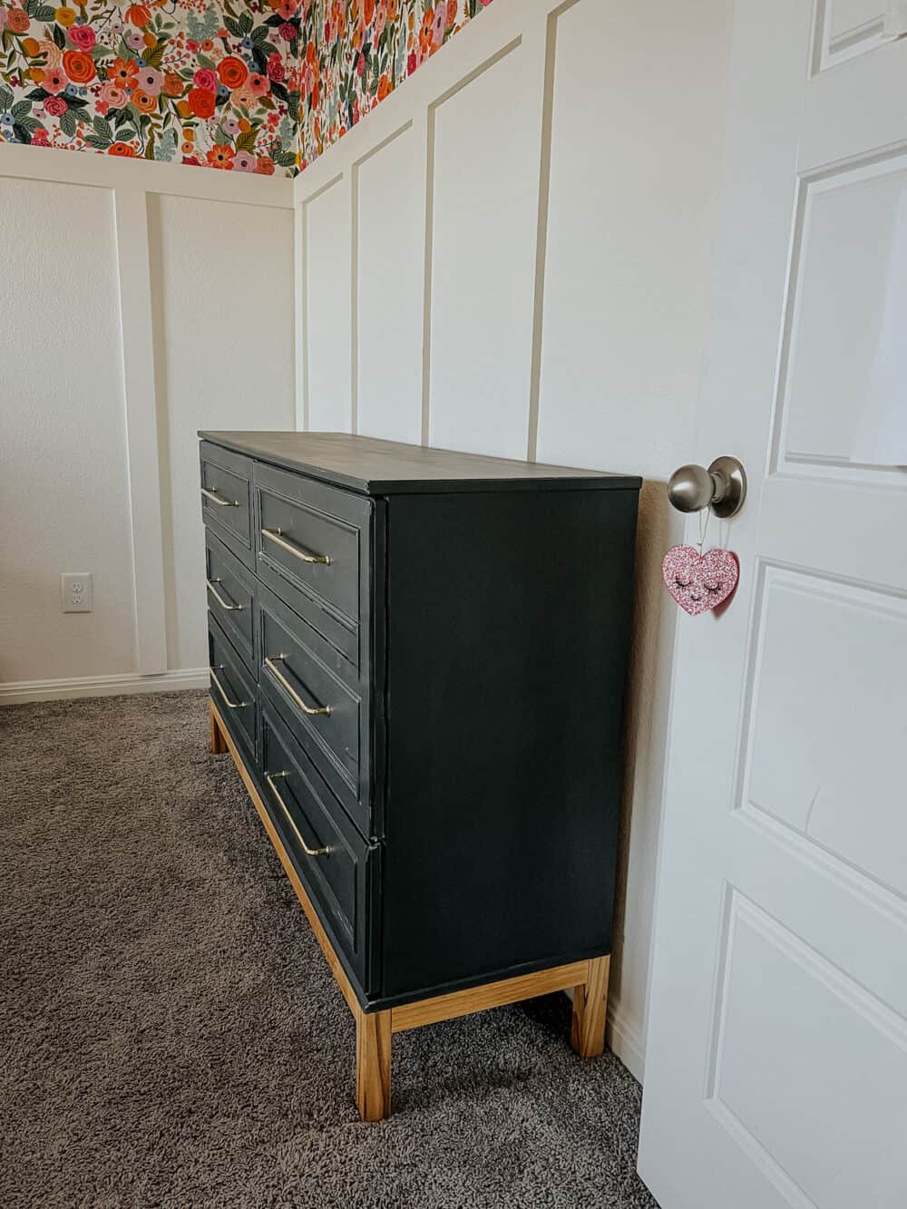 Black IKEA dresser in a girls' room with floral wallpaper