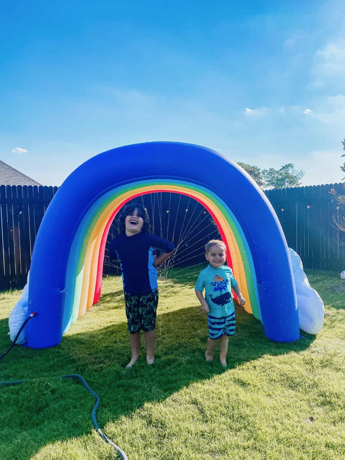 two young boys in front of a rainbow arch sprinkler