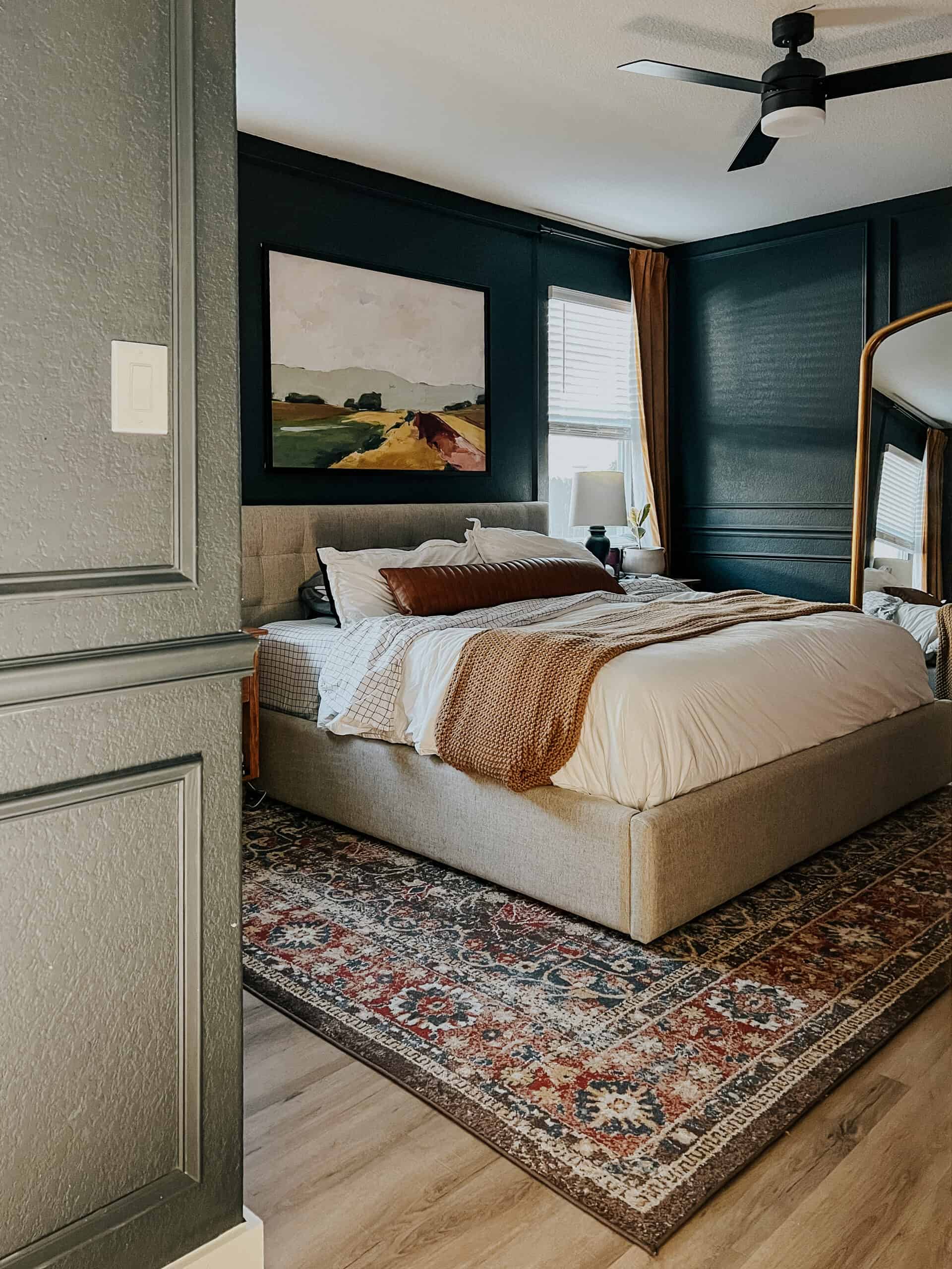 A master bedroom with dark blue walls and white bedding 