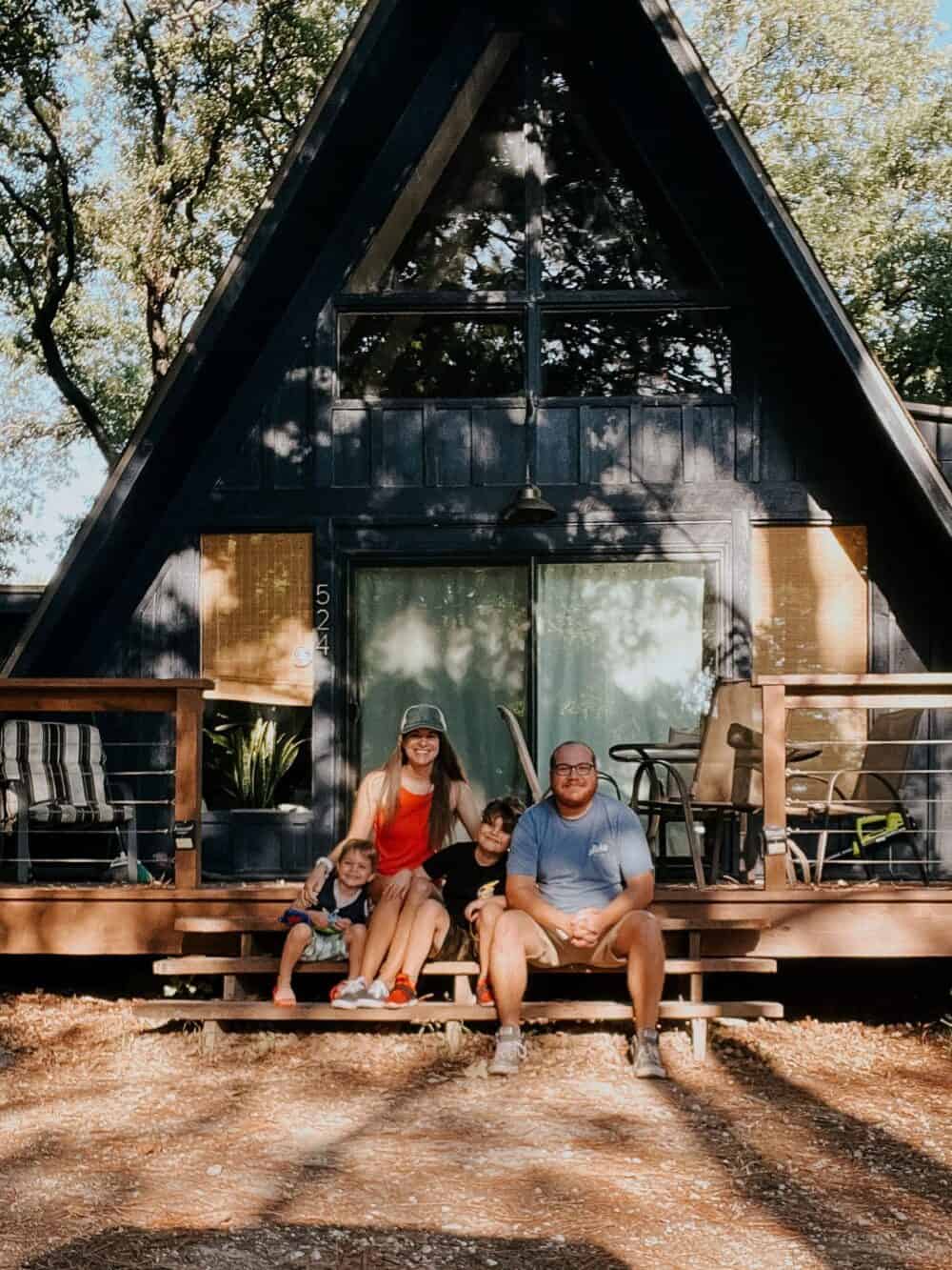 Famiily posing in front of an A-Frame cabin in Granbury, TX