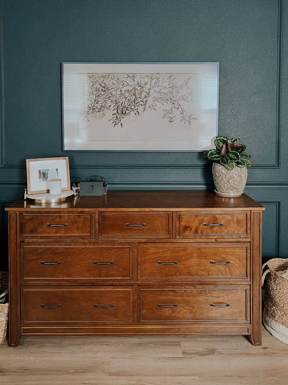 Bedroom with dark blue walls and a Frame TV hanging above a dresser 