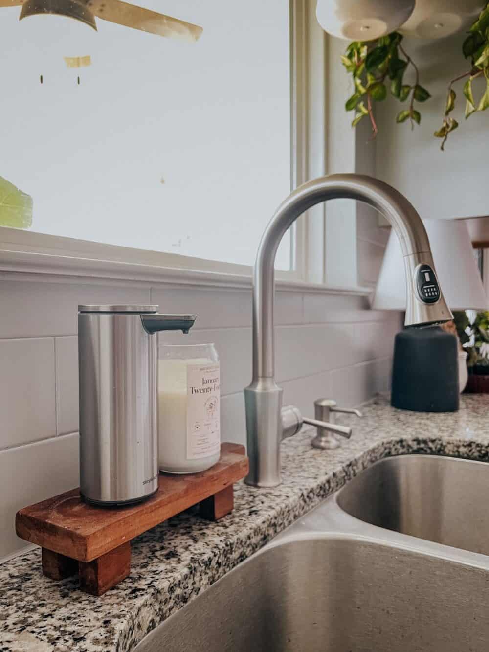Kitchen sink with a wood pedestal holding soap and a candle 