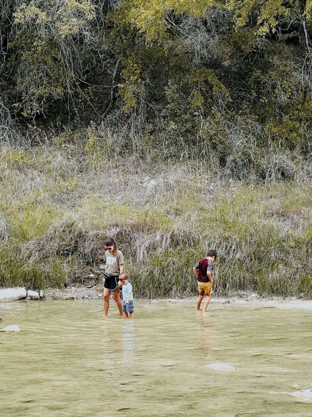 Woman and two boys wading in the water at Dinosaur Valley State Park in Glen Rose