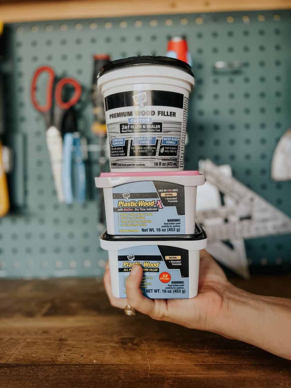 woman's hand holding a stack of wood filler containers 