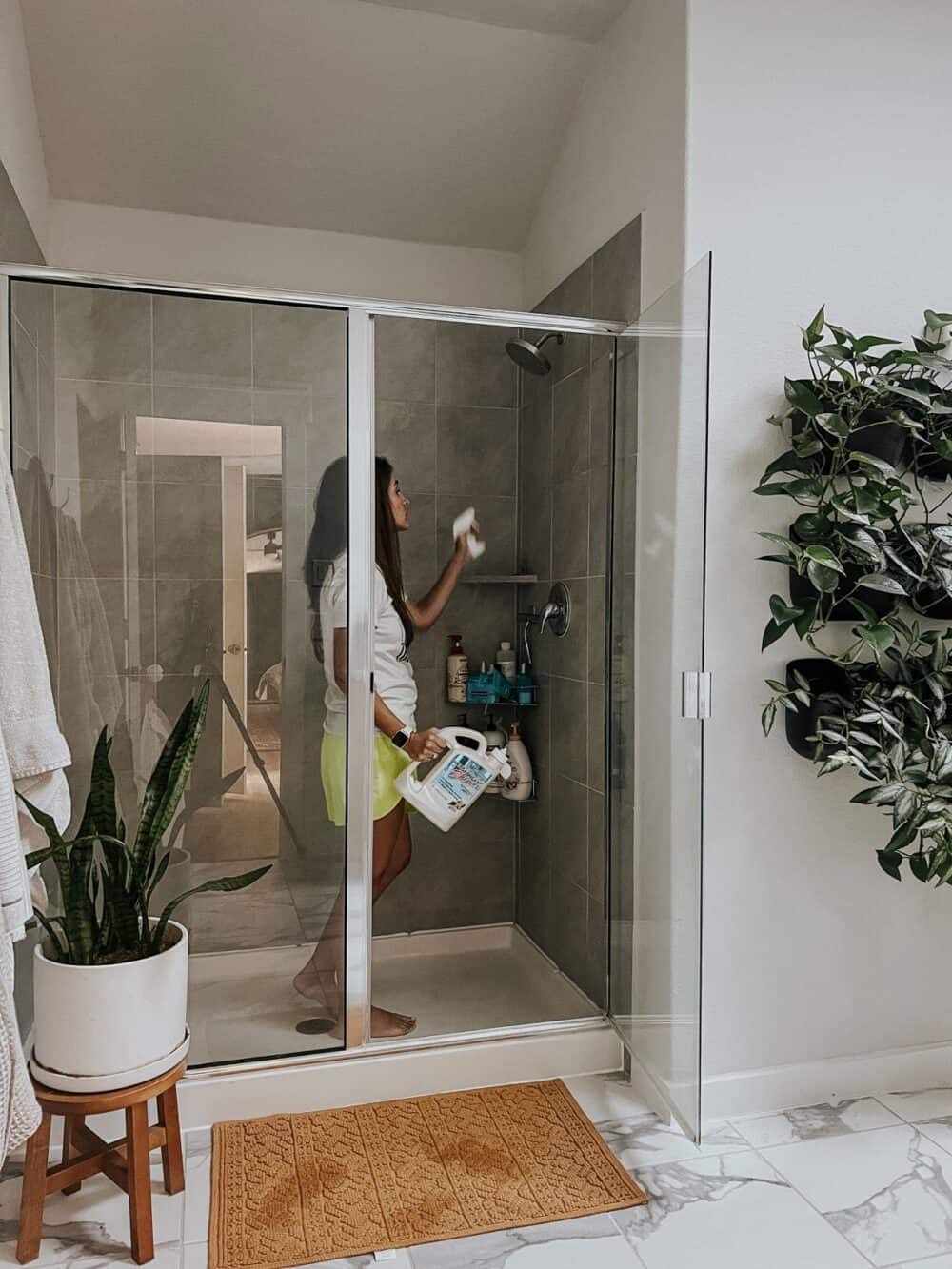 woman using wet and forget shower cleaner on a shower 