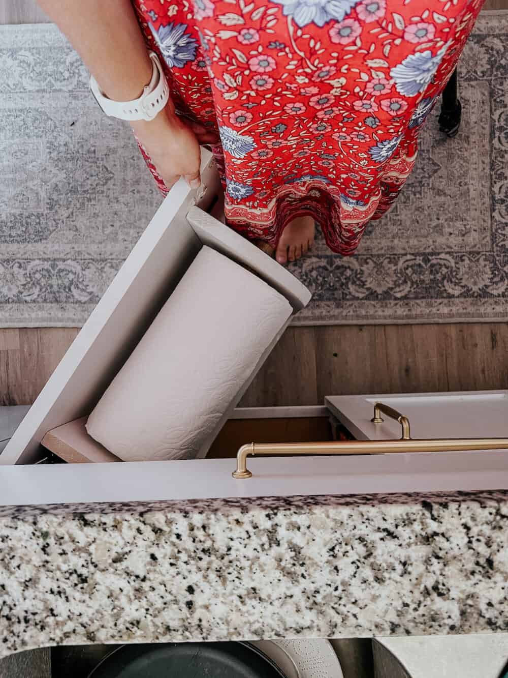 overhead view of a cabinet under the kitchen sink with a DIY paper towel holder on the door 