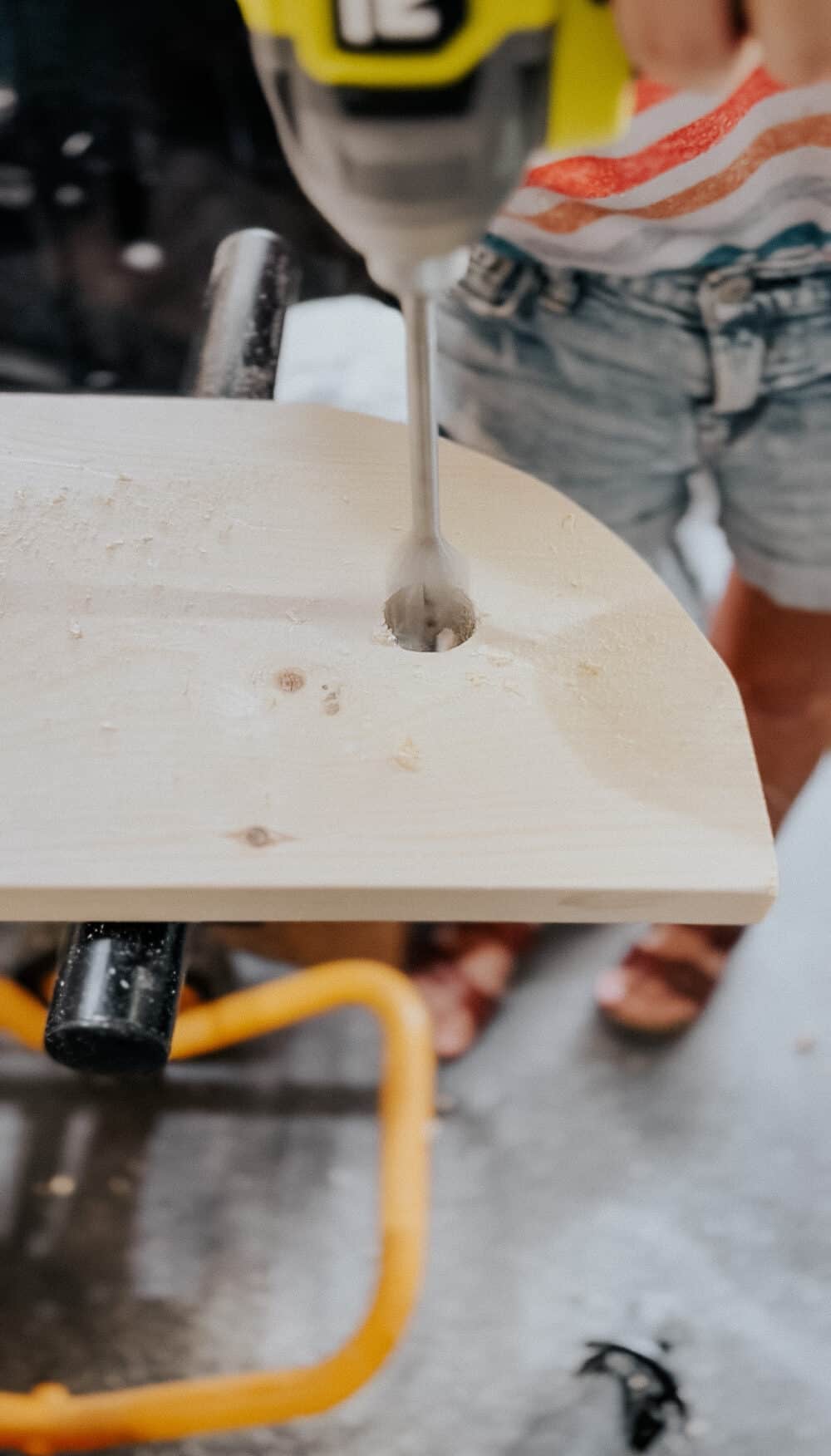 woman's hand drilling a hole in a piece of wood 