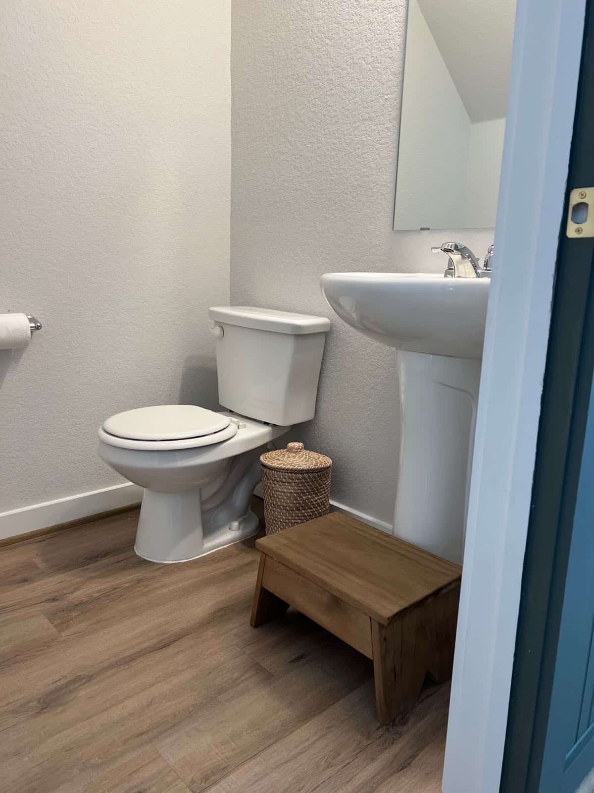 Small powder room with a wooden step stool in front of a pedestal sink