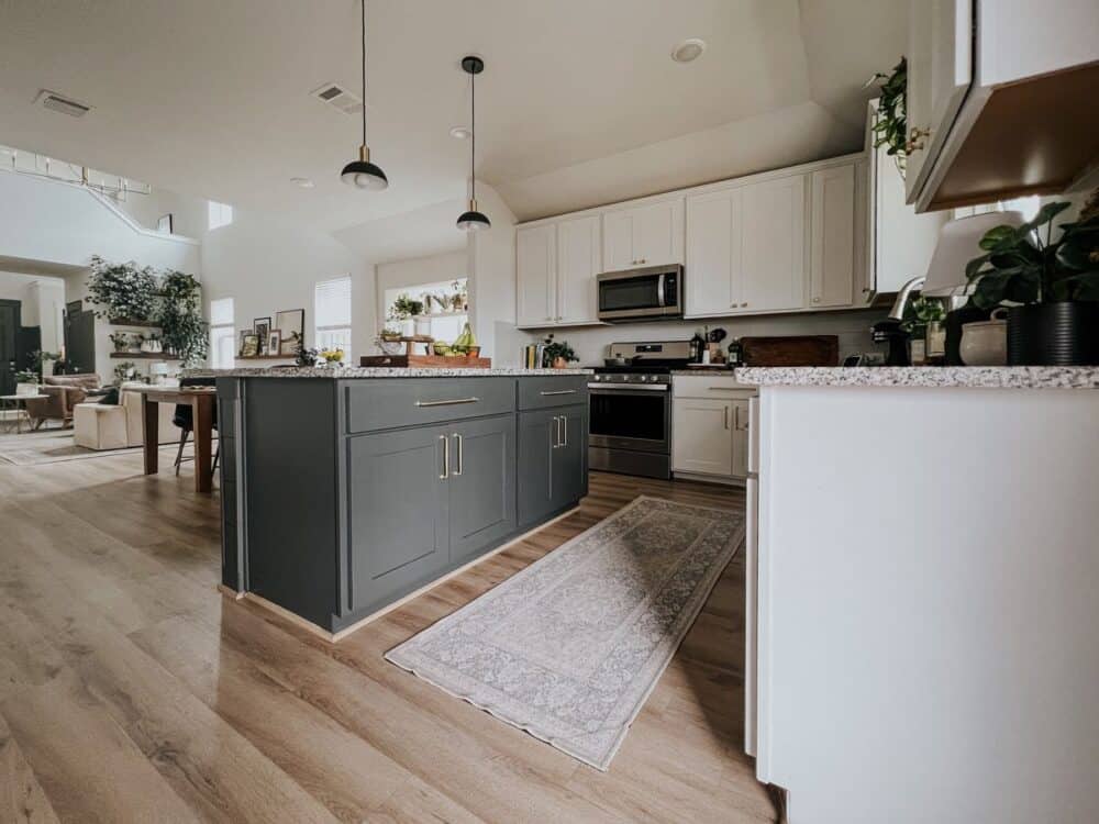 Kitchen with white perimeter cabinets and a black kitchen island 