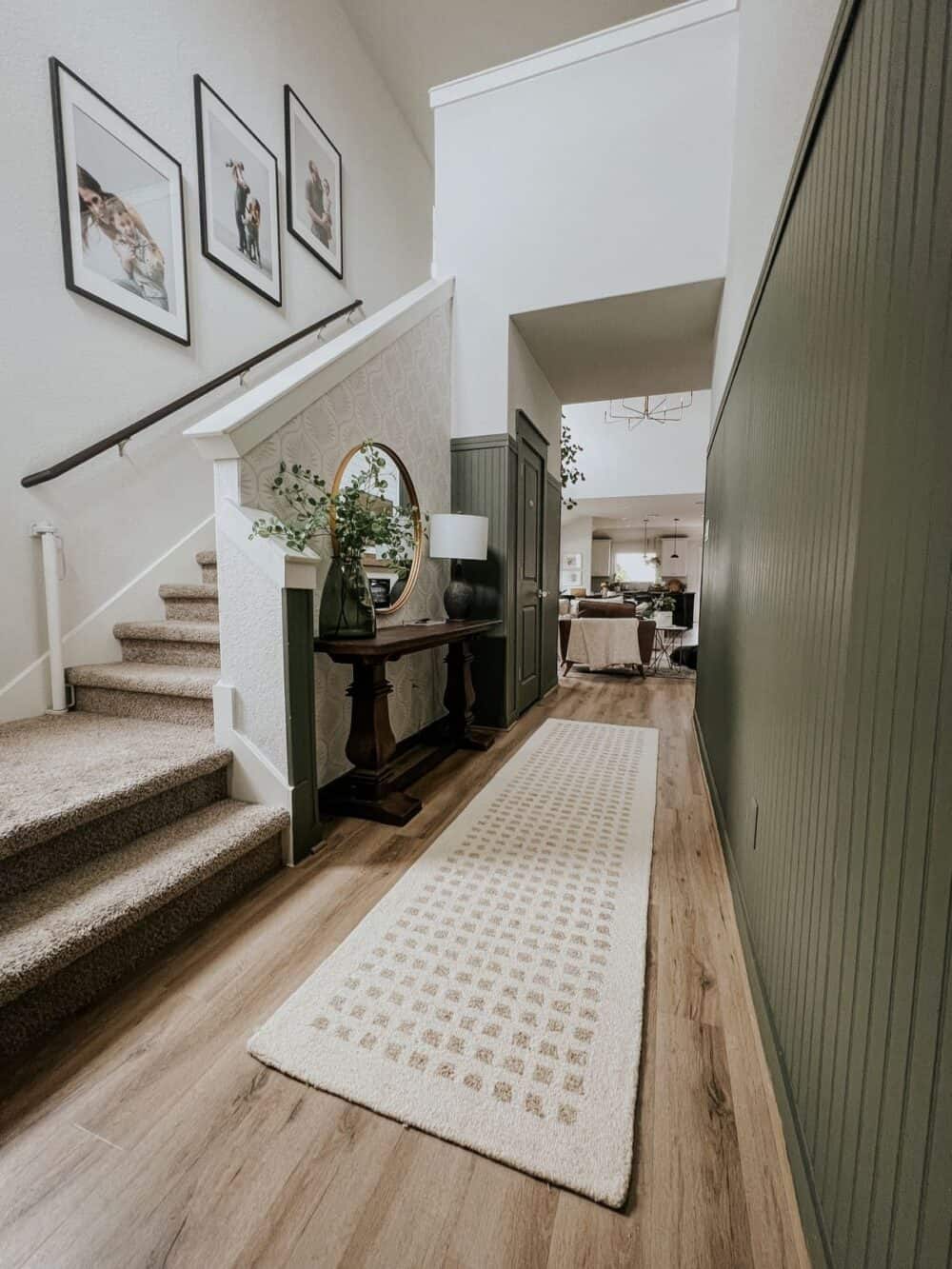 entry with green bead board paneling and a neutral checkered rug