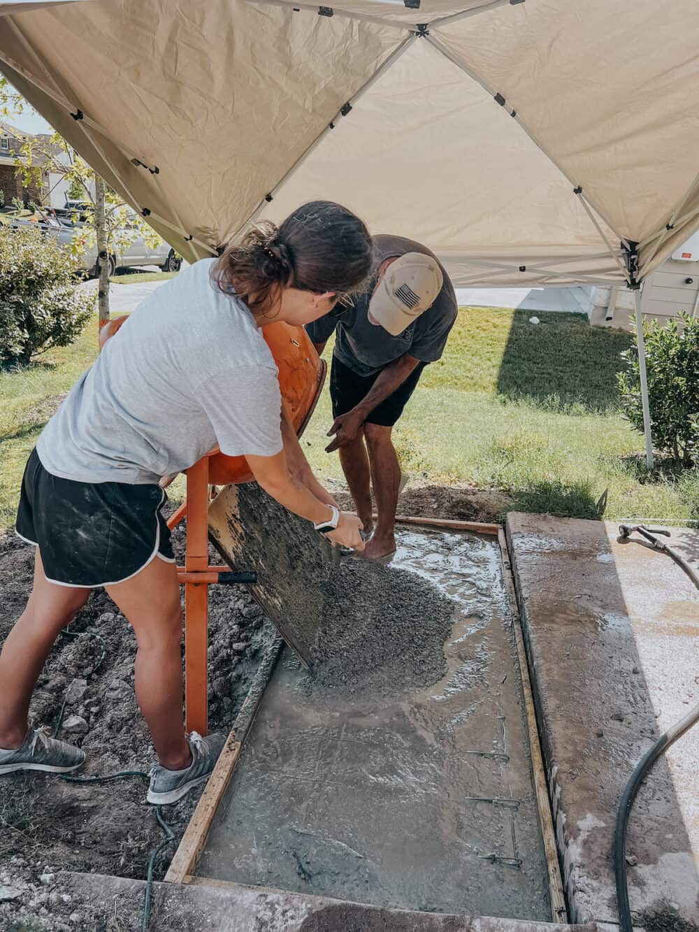 Man and woman pouring concrete for DIY porch step
