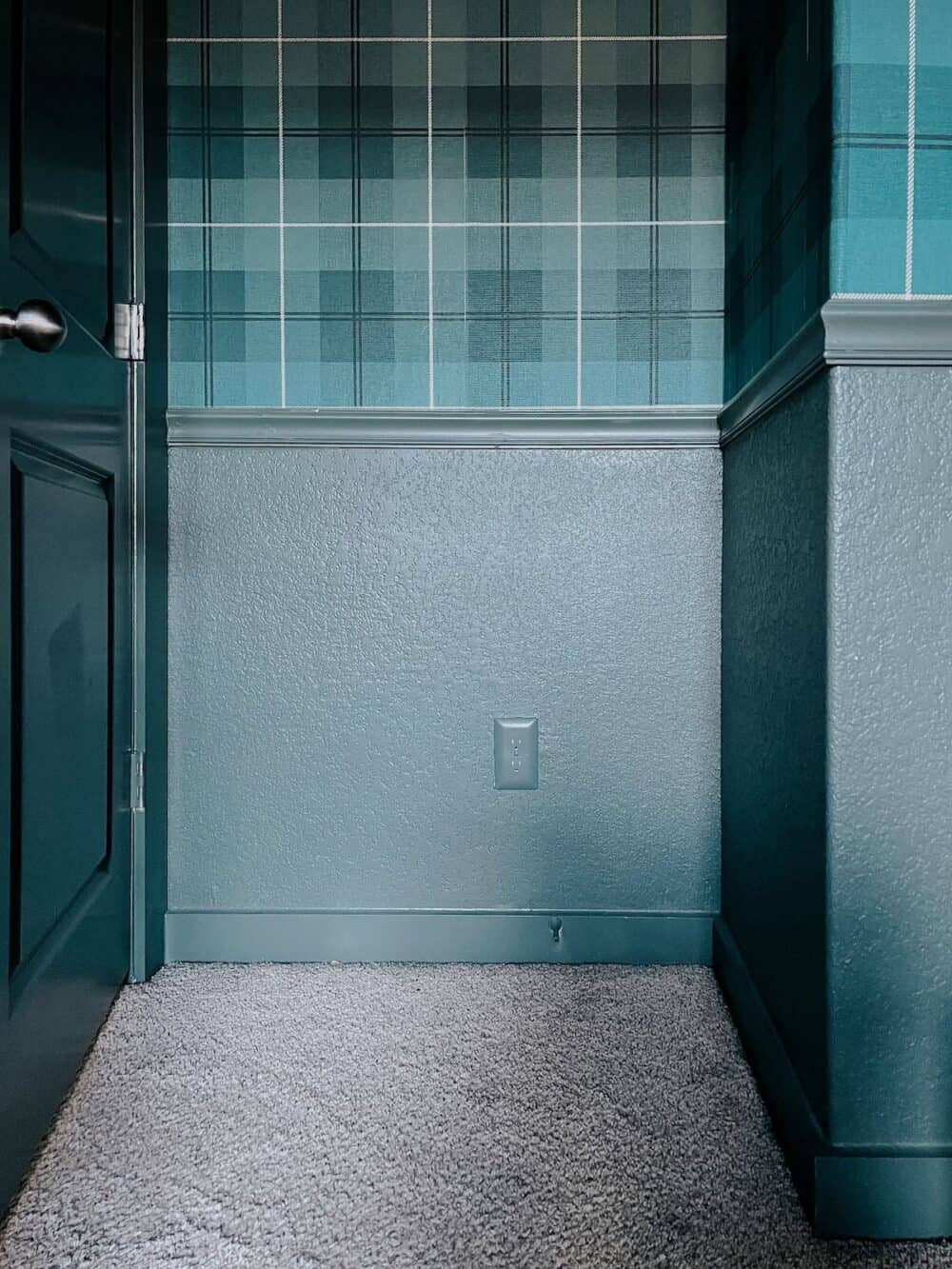 green bedroom with plaid wallpaper and a paintable outlet cover on the wall