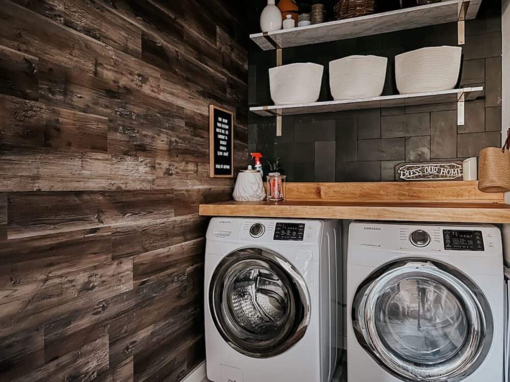 laundry room with black tile and a wood accent wall 