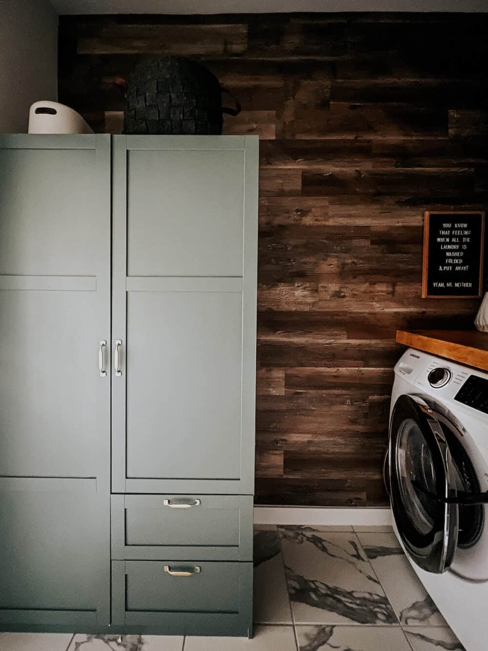 a laundry room with a storage cabinet painted sage green