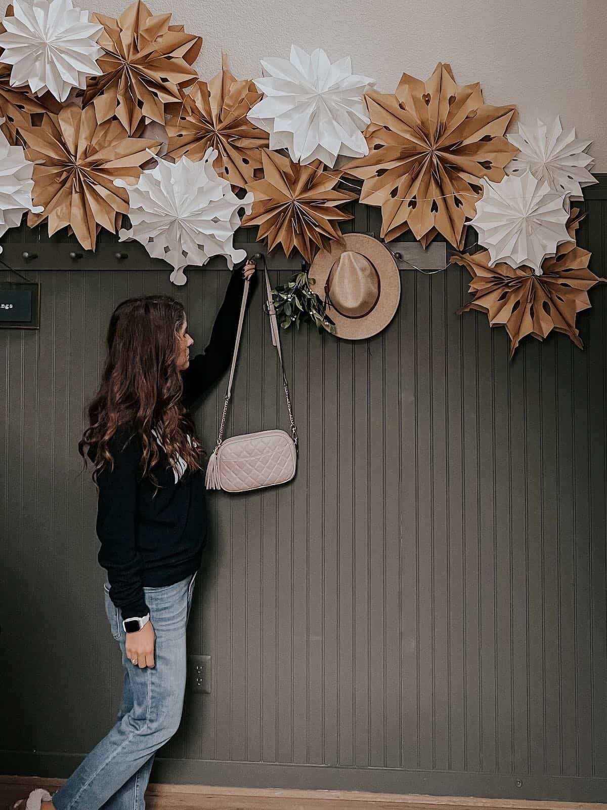 Woman in home entry that has a large paper bag snowflake garland