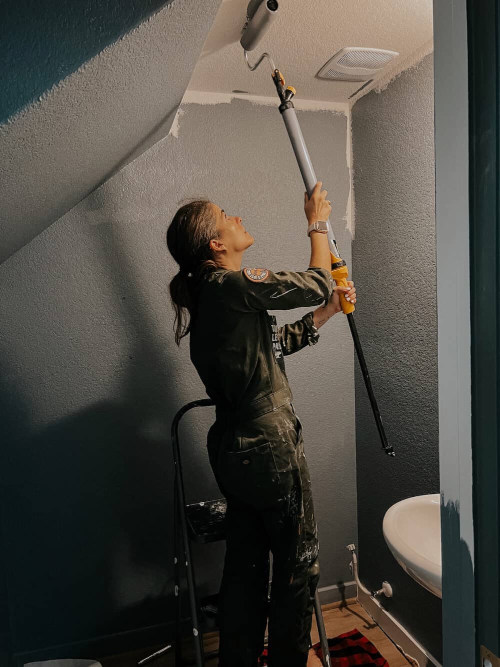 woman using an EZ roller to paint a ceiling