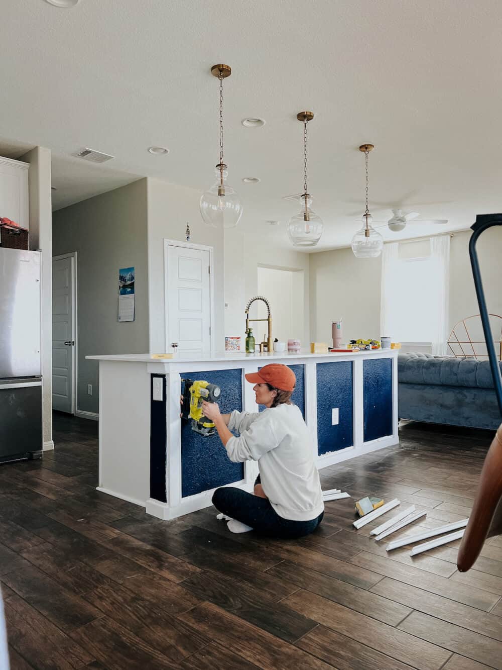 Woman attaching trim to a blue kitchen island 