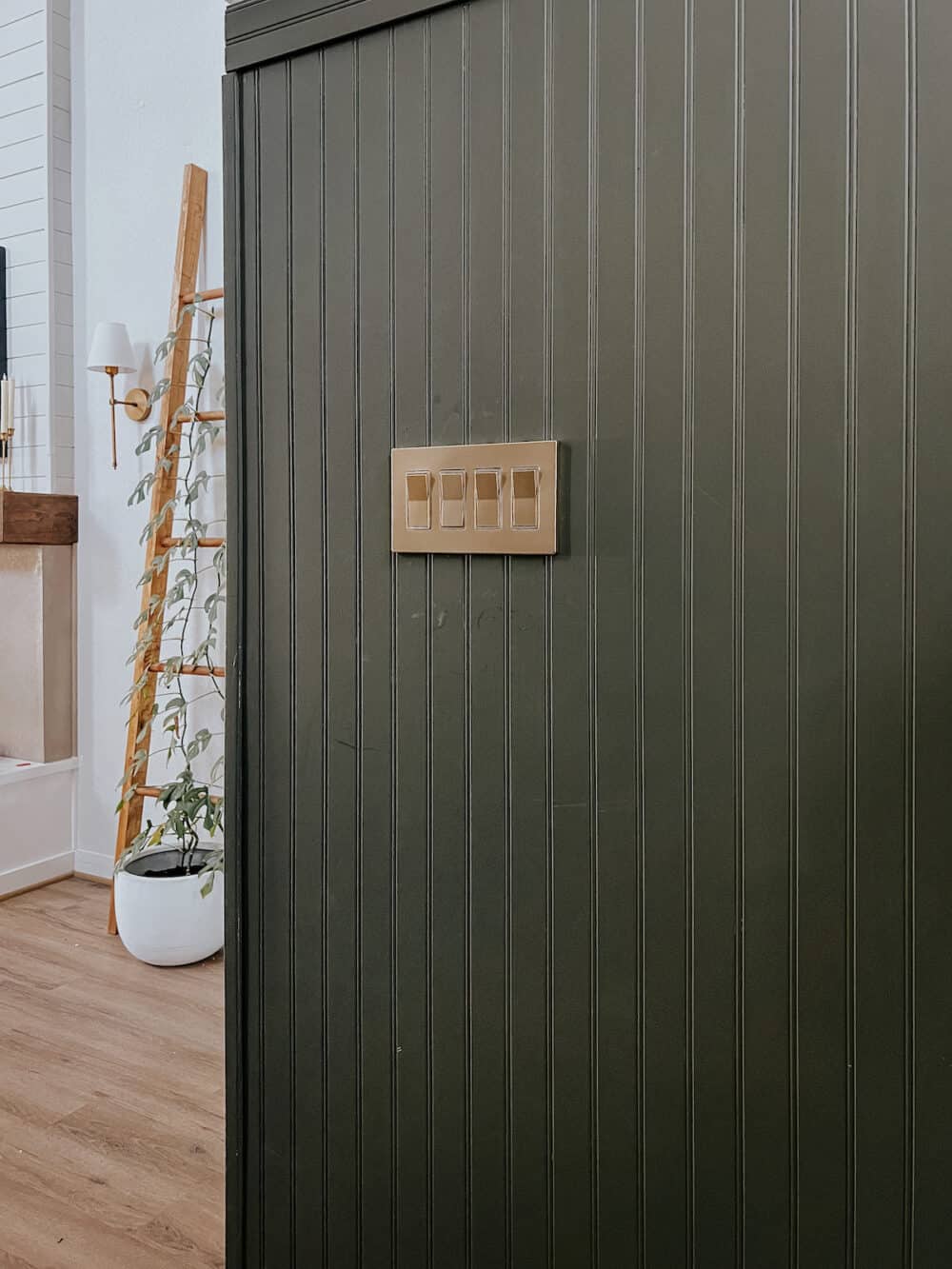 green bead board wall with gold light switch and plates 