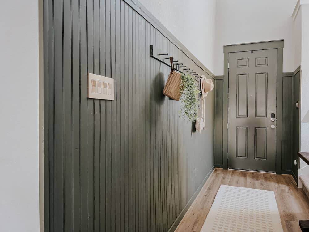 home entry with green paneled walls and a gold light switch 