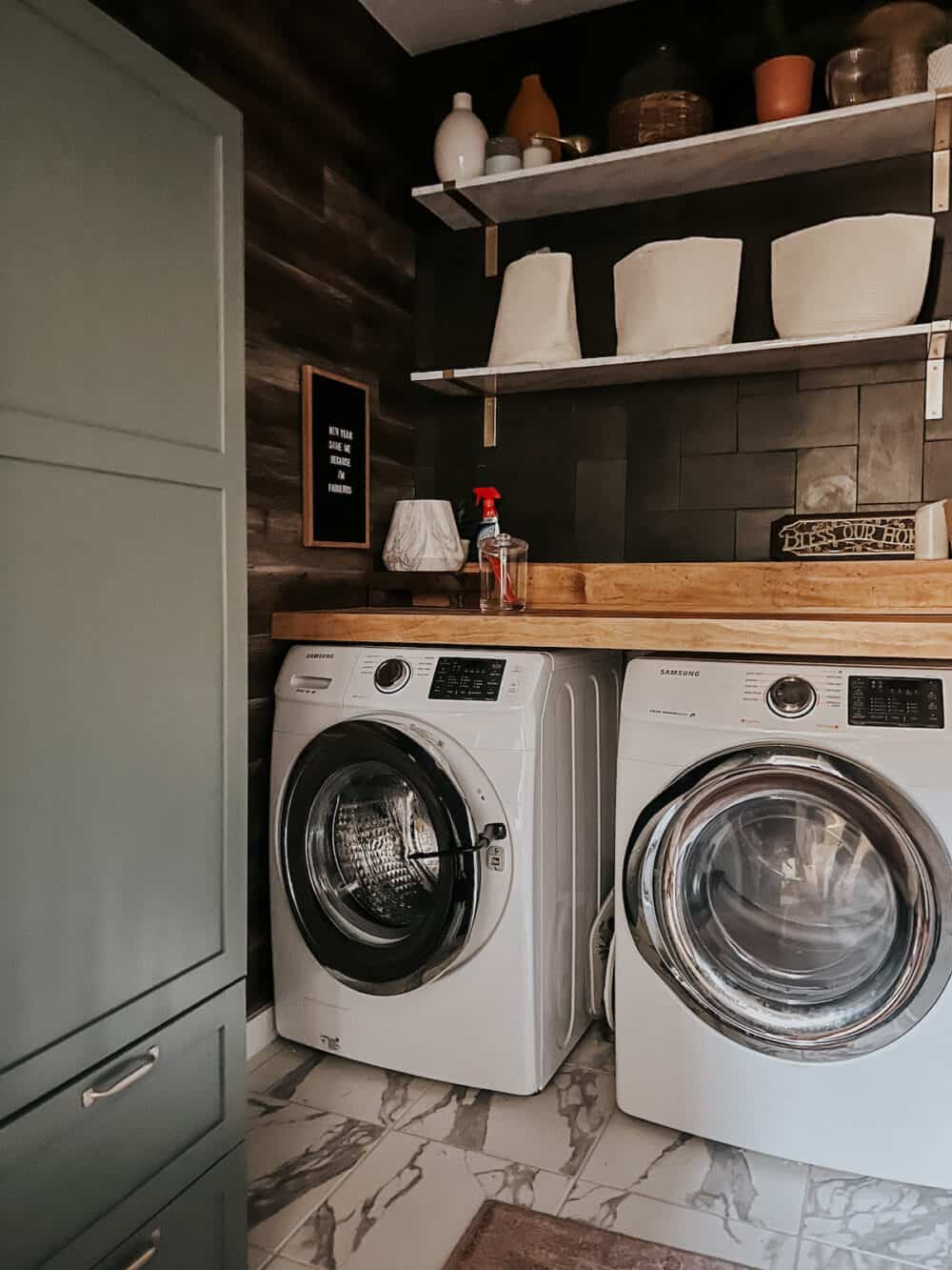 laundry room with a large green cabinet and front load washer and dryer. Washer is propped open with a washer door prop. 
