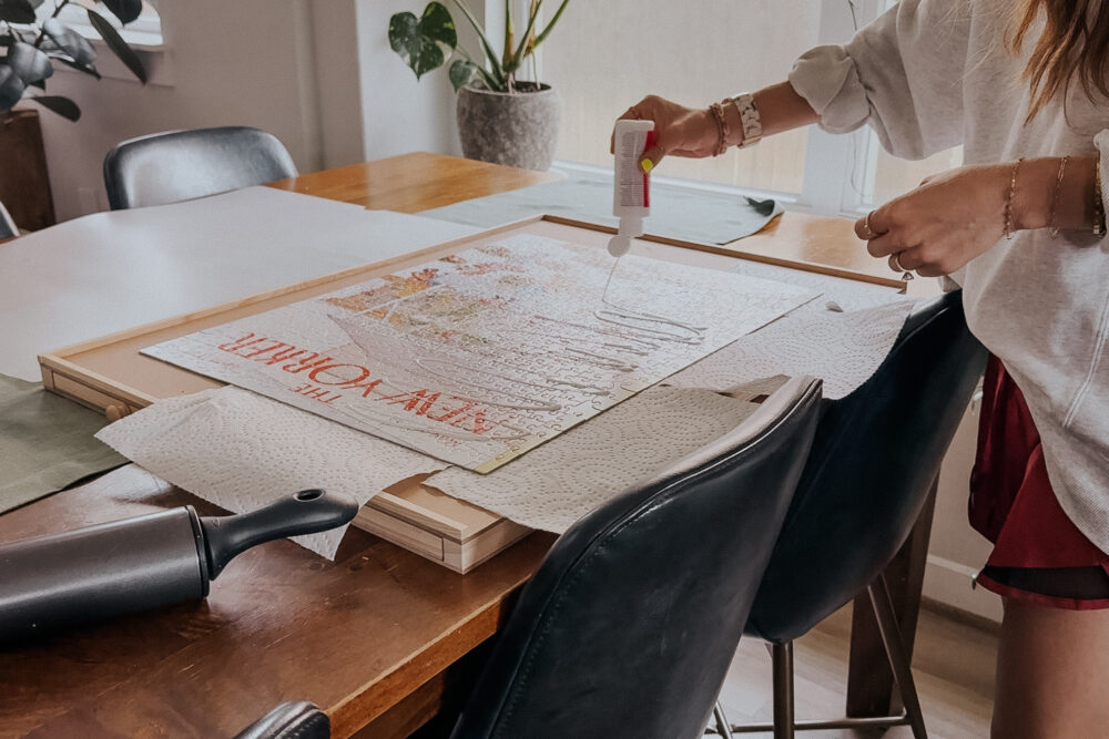 woman adding puzzle glue to a completed jigsaw puzzle 