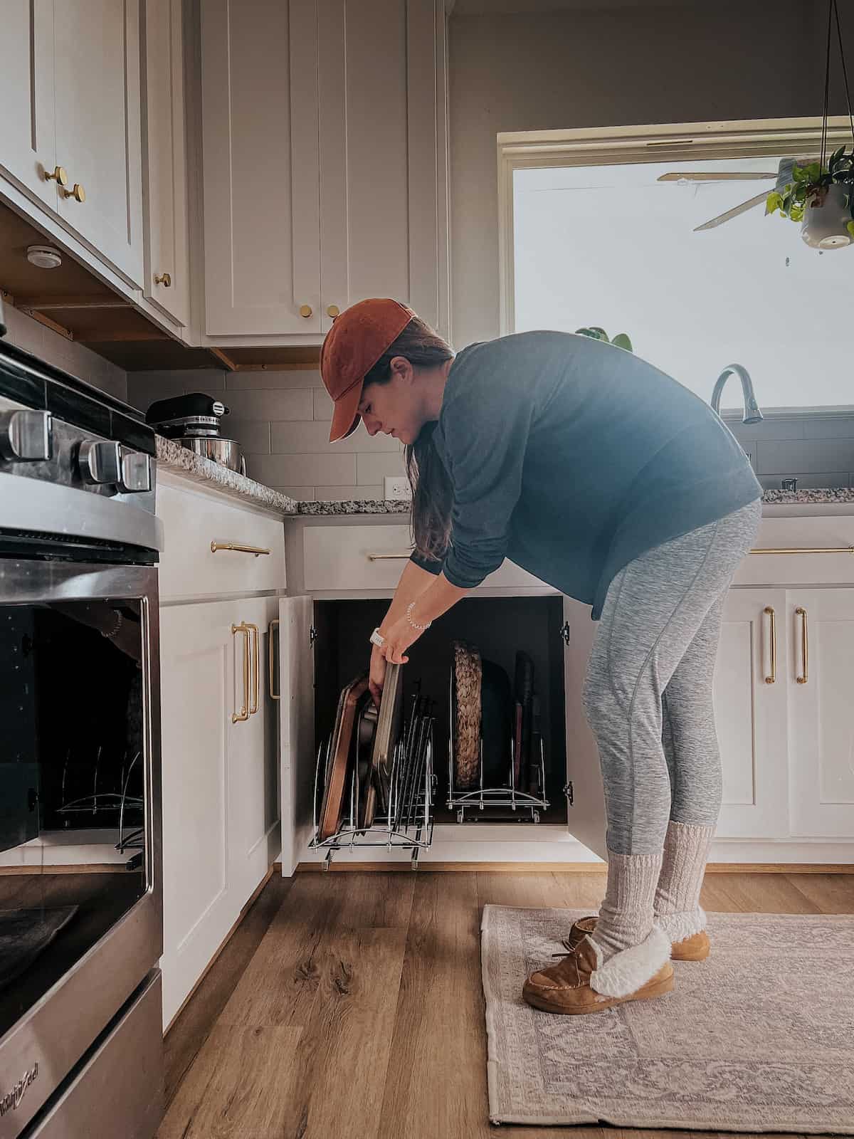 woman grabbing a cookie sheet out of an organized cabinet