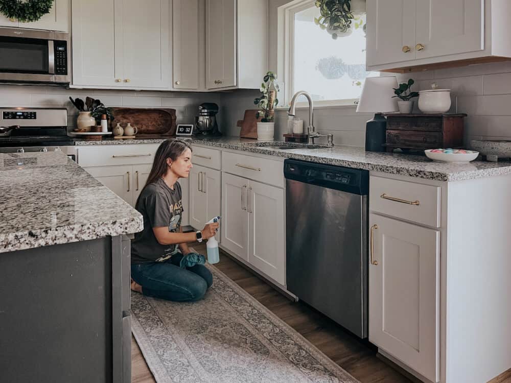 Woman sitting in a kitchen cleaning kitchen cabinets 