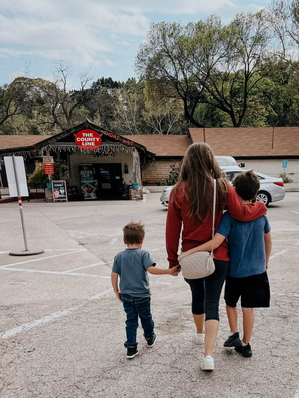 woman and two boys walking towards a restaurant 