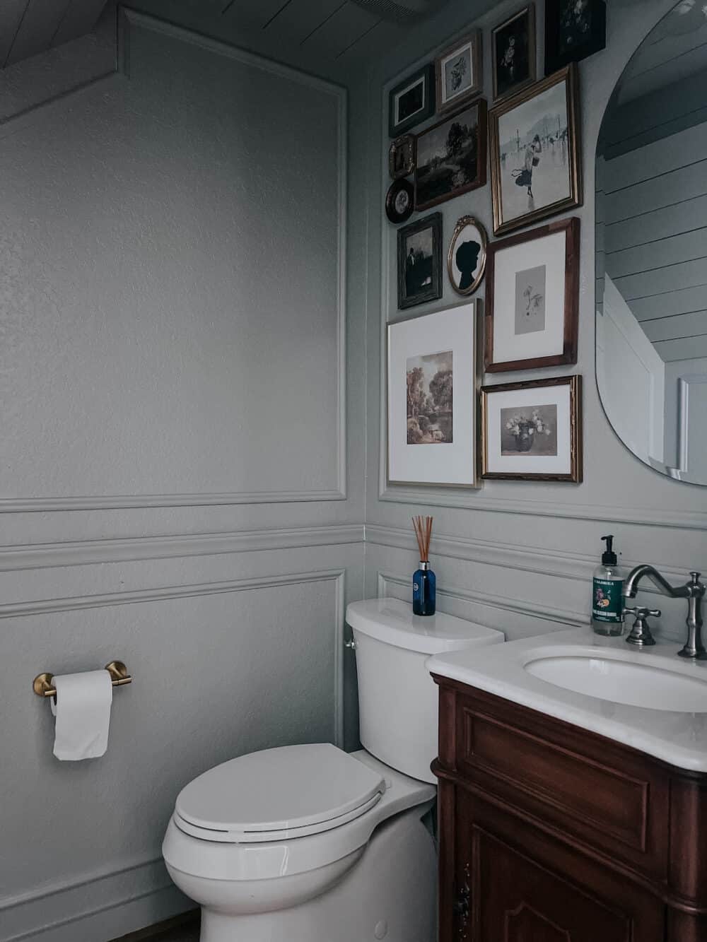 a small powder room with a gallery wall and blue gray wallls