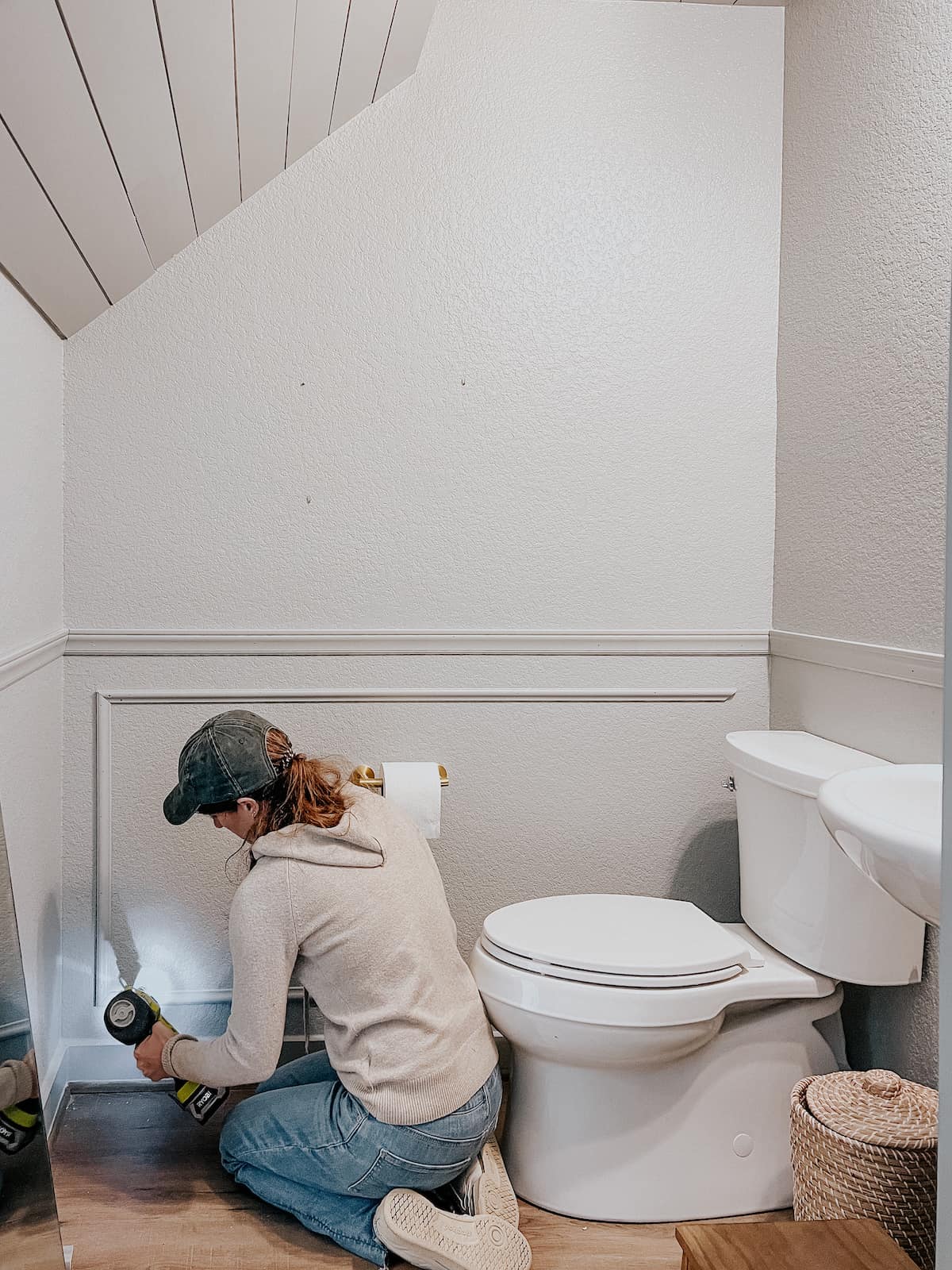 woman installing picture frame molding in a powder room 