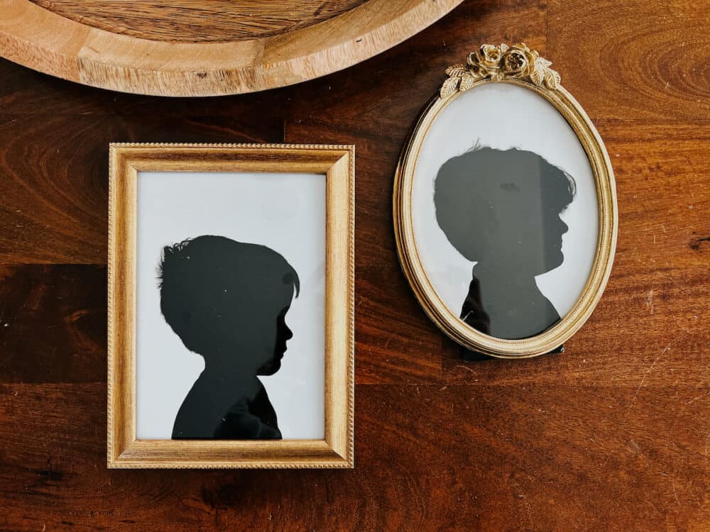 two silhouette art prints framed and laying on a table 