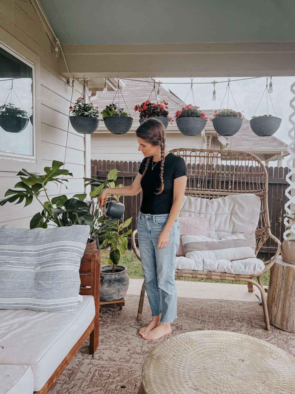 woman on a small back patio watering a plant 