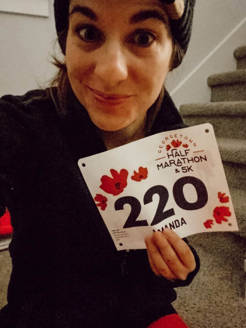 woman posing with a race bib for a half marathon