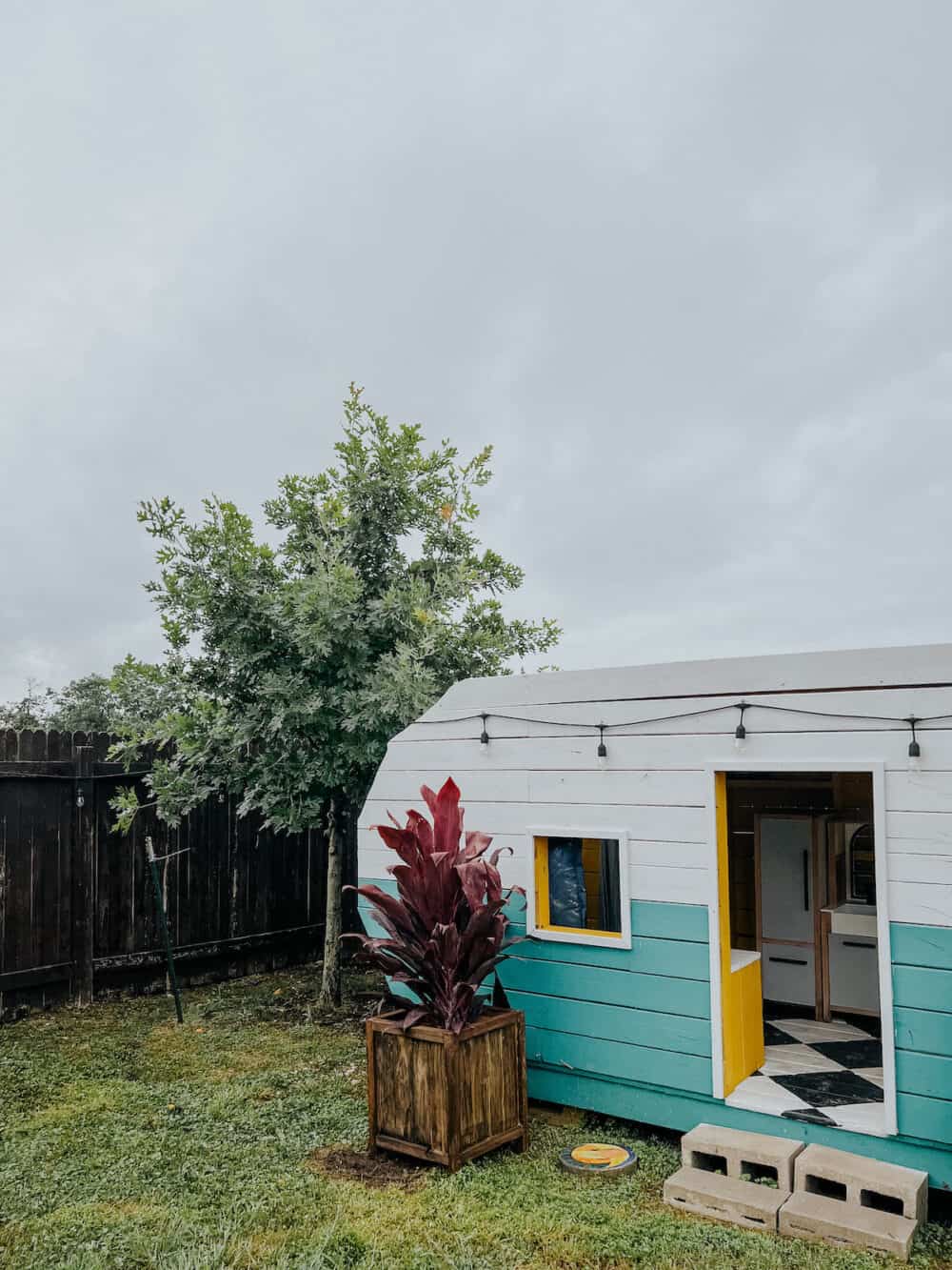 a playhouse camper with a DIY wood planter box next to it 