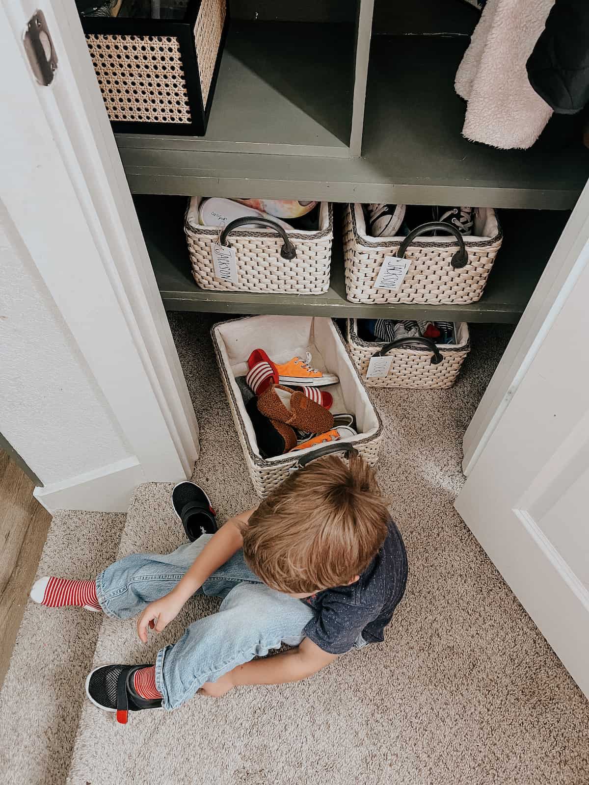 overhead view of a young boy putting on shoes in front of a coat closet