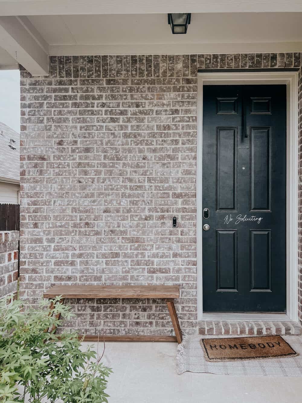 front porch with large, empty brick wall