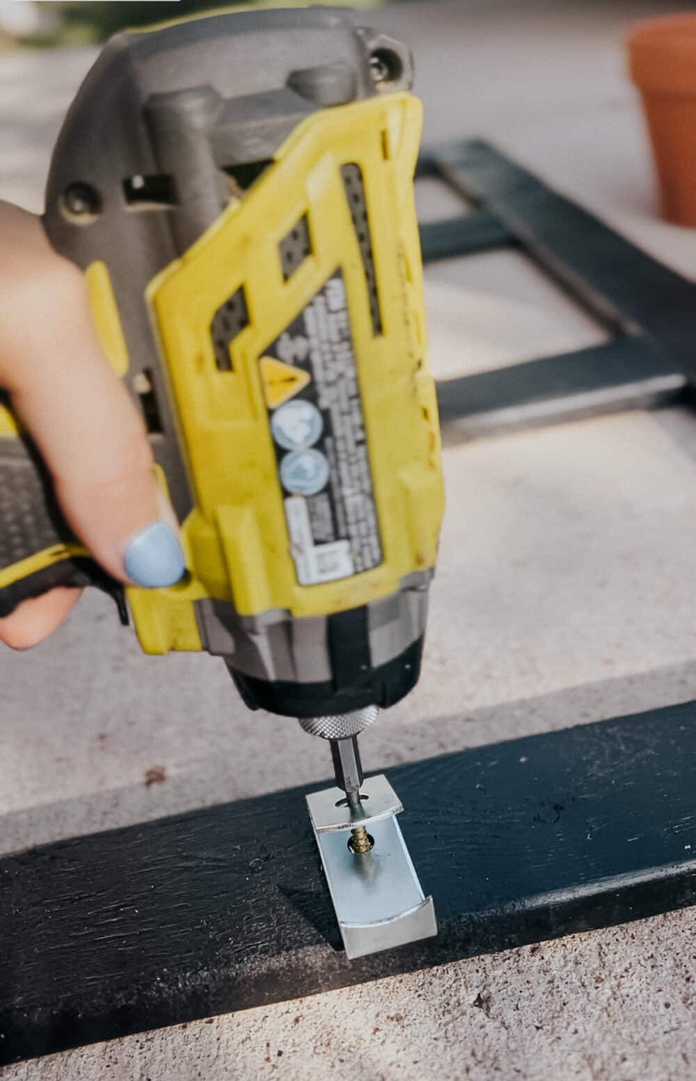 close up of a drill attaching a plant clip to a frame