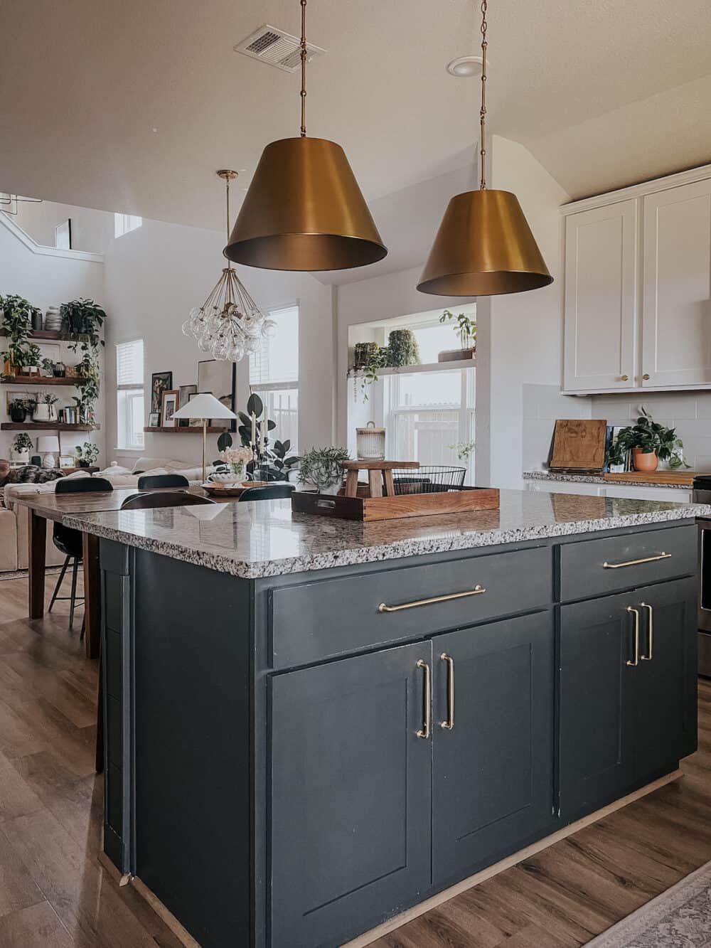 black kitchen island with gold pendants above it 