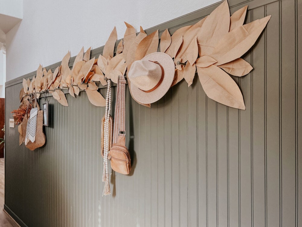 an entry way with a paper bag leaf garland hanging above a peg rail 