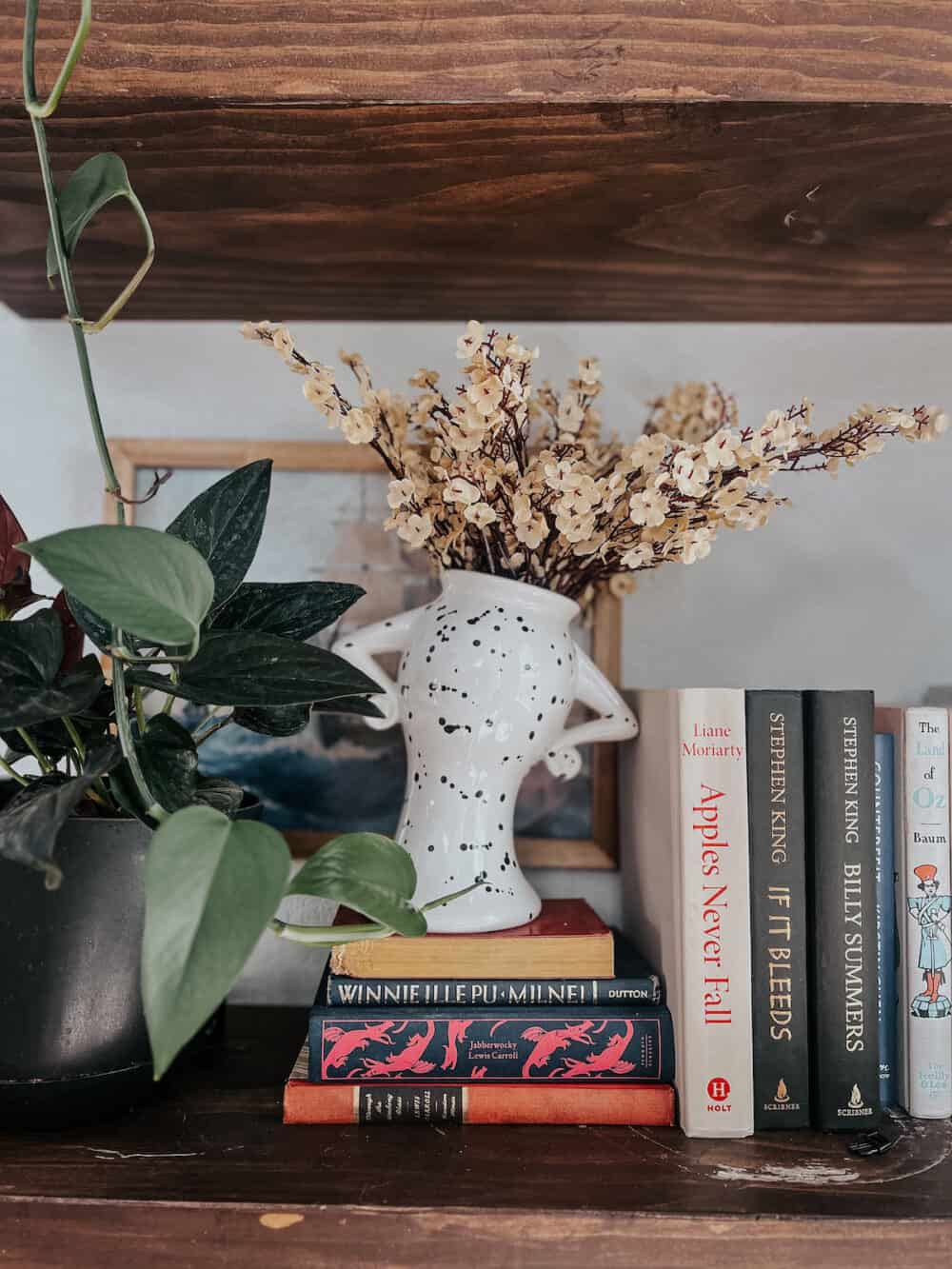 a dotted vase on a shelf with faux fall flowers