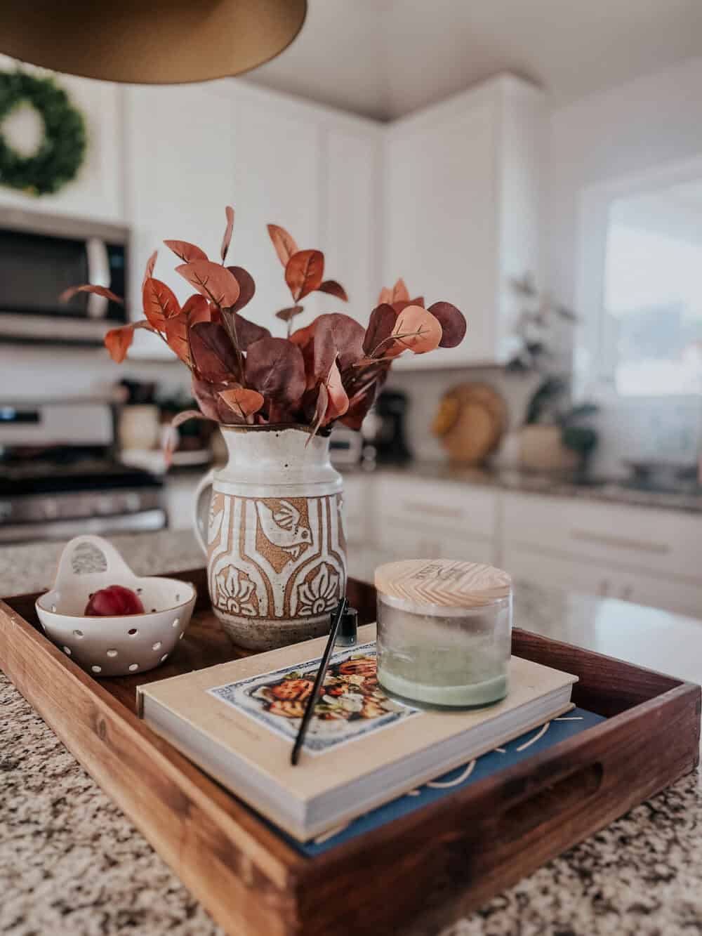 kitchen island with a tray and faux fall leaves in a pitcher