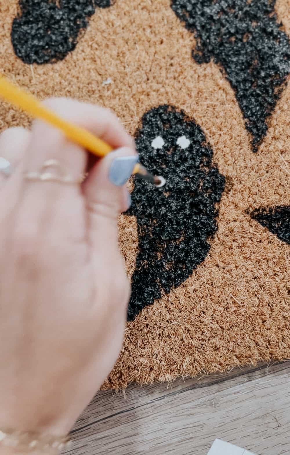 woman's hand painting eyes on a ghost on a door mat
