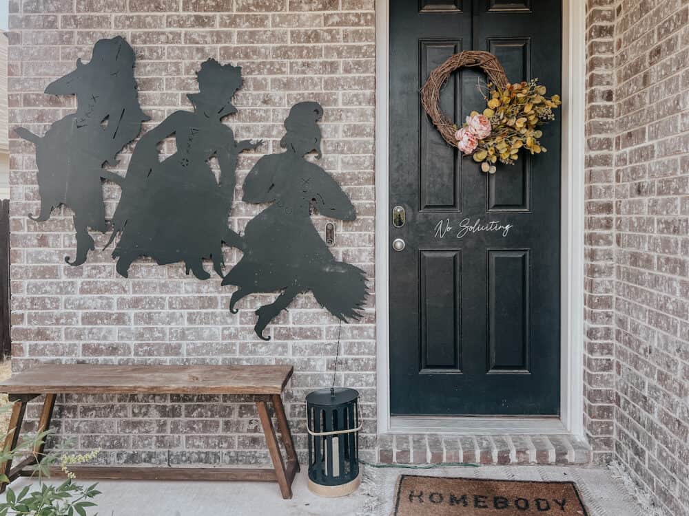 wooden silhouette of the Hocus Pocus witch sisters on the side of a house