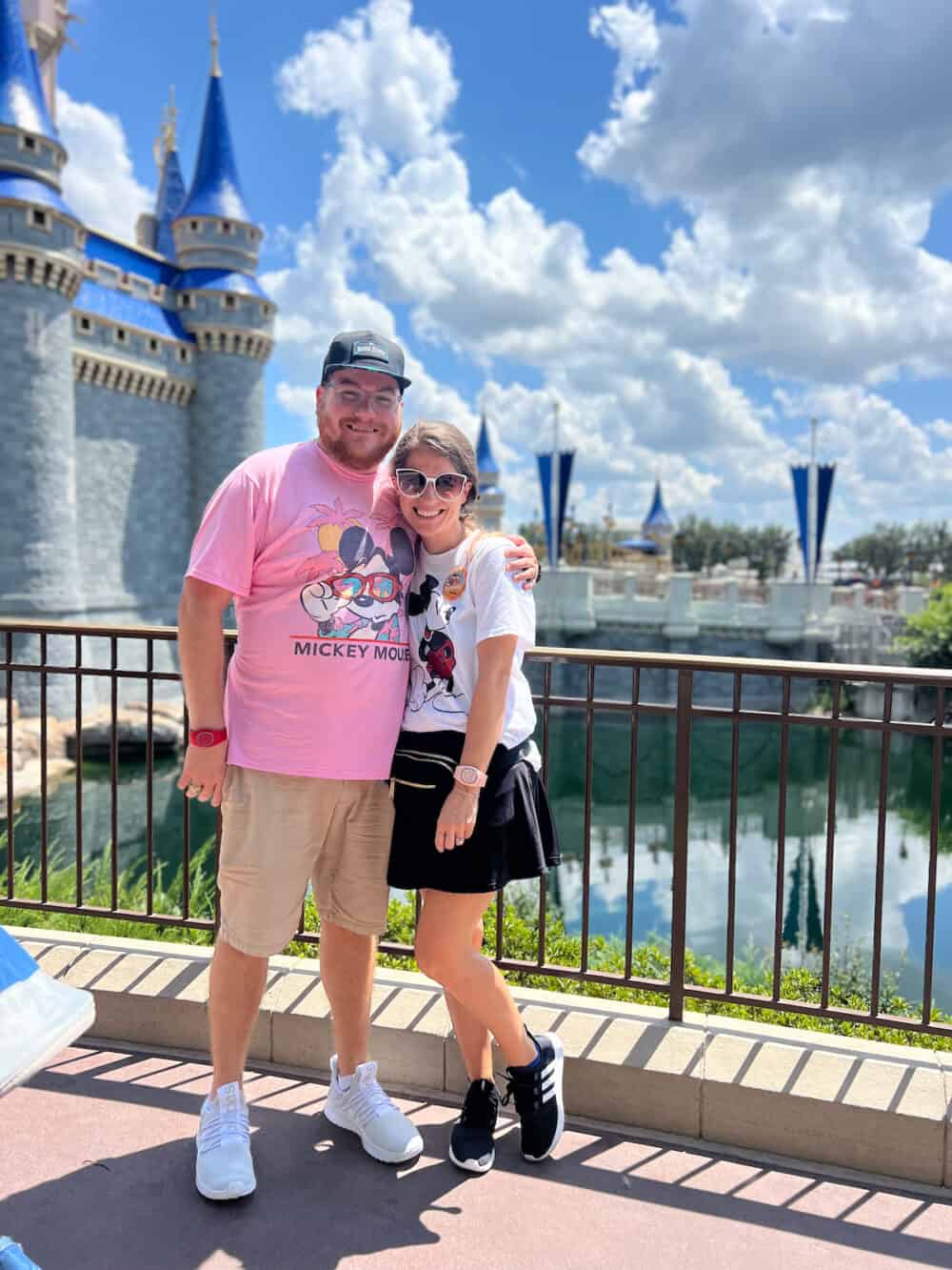 adult couple posing in front of Cinderella's castle, with Disney World outfit ideas 
