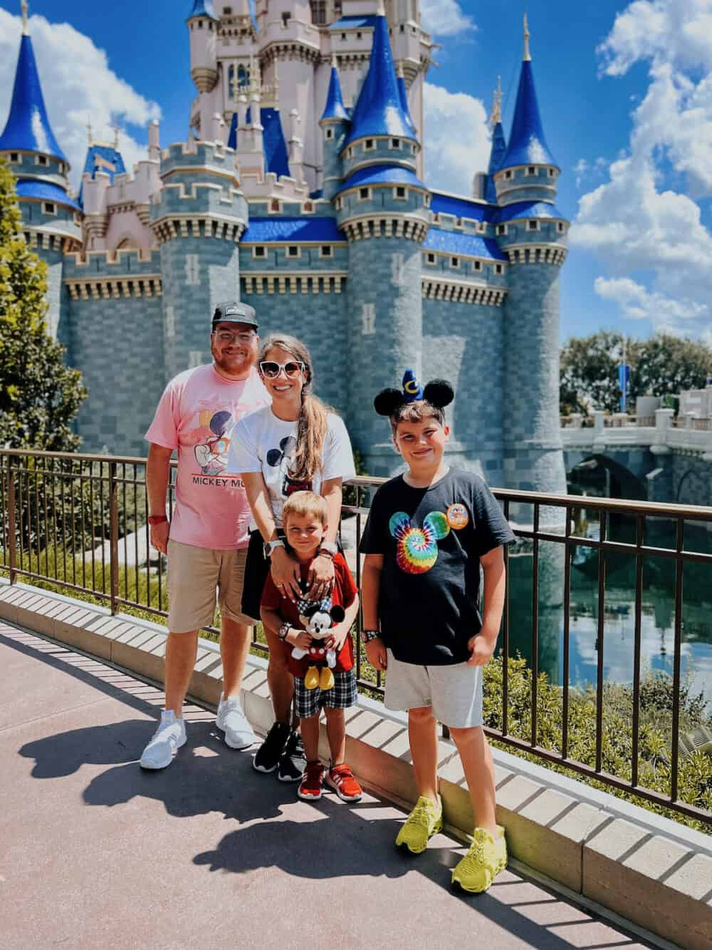 family of four standing in front of the Cinderella castle at Magic Kingdom in Disney World 