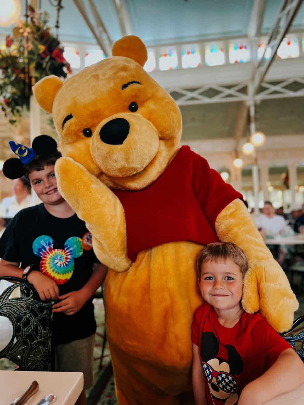 two young boys posing with Winnie the Pooh at Crystal Palace in Disney World 