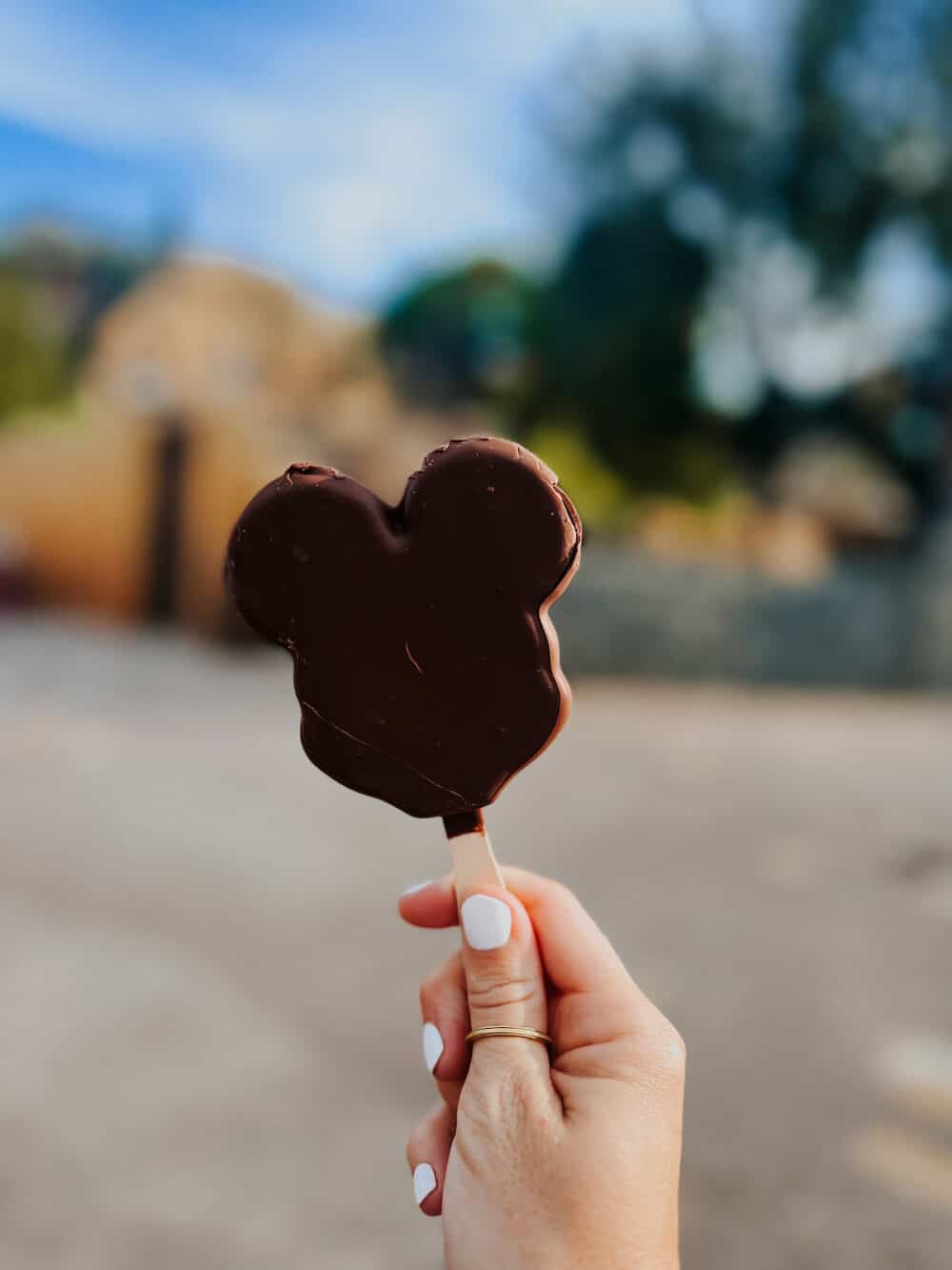 woman's hand holding a mickey shaped ice cream bar 