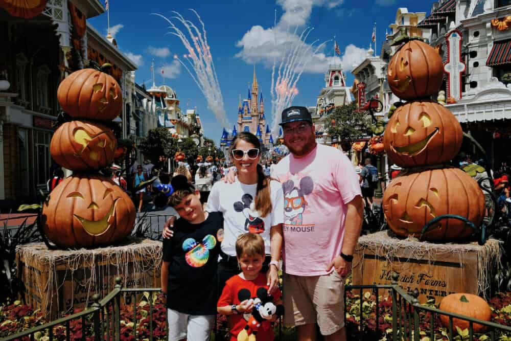 family posing on Main Street in Disney world with fireworks in the background 