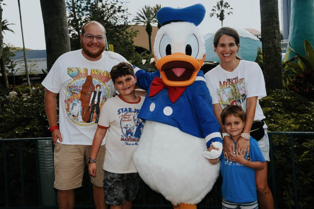 Family of four posing with Donald Duck in Hollywood Studios in Disney World 